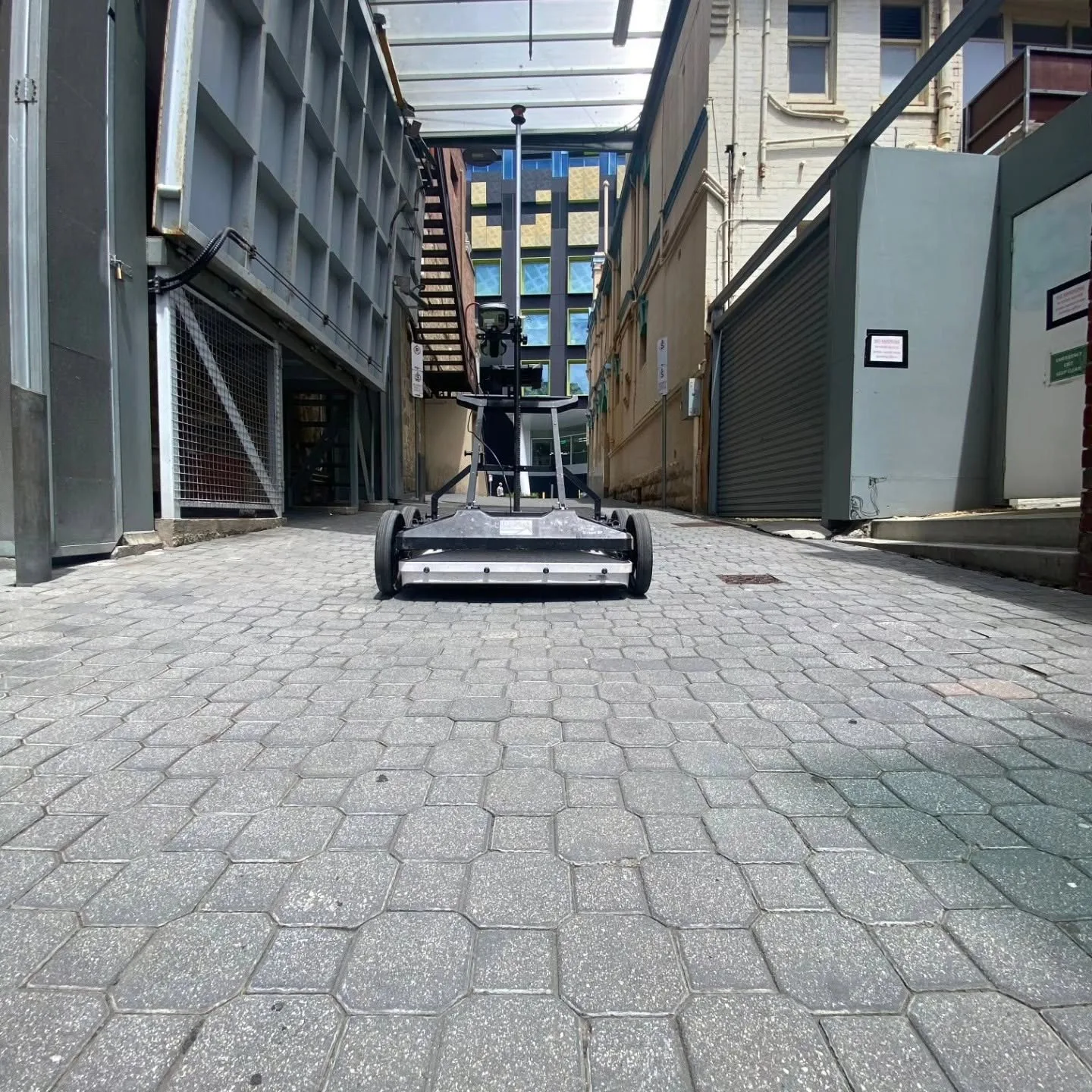 Utility locating equipment working through a narrow paved laneway